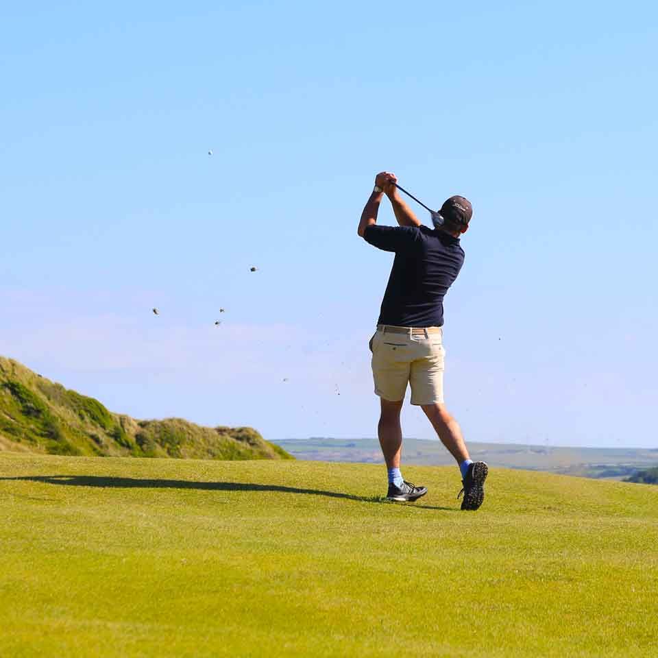 A golfer striking a ball on the St Enedoc's Golf Club's Church Course.